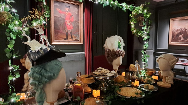 Stylised Georgian wigs on mannequin heads preside over a Christmas Feast at Quebec House. A portrait of General James Wolfe is in the background